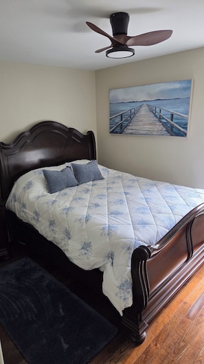 Un dormitorio con una cama de madera, un ventilador de techo y una pintura de un muelle.