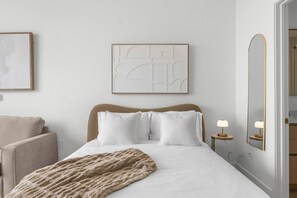 A bedroom with a bed, a headboard, a bedside table with a lamp, a mirror, and a framed abstract artwork on the wall. - Modern Studio at The Standard Miami (Miami)