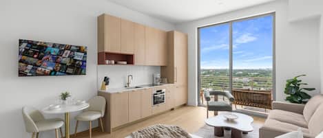 A modern apartment with a kitchen, dining area, and living room, featuring large windows and a city view.