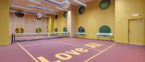 Pistes de tennis amb xarxa, seients i mur amb forats circulars.