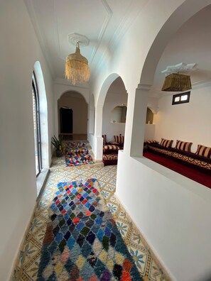 A corridor with a patterned carpet, arched ceilings, and a hanging light fixture.