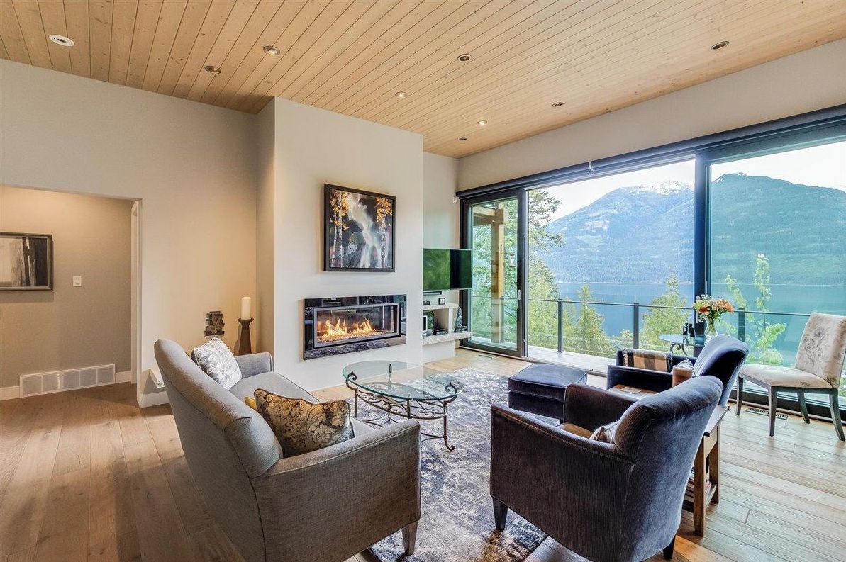 Ein modernes Wohnzimmer mit Kamin, bequemen Sitzmöglichkeiten und einem großen Fenster mit Blick auf die Berge.