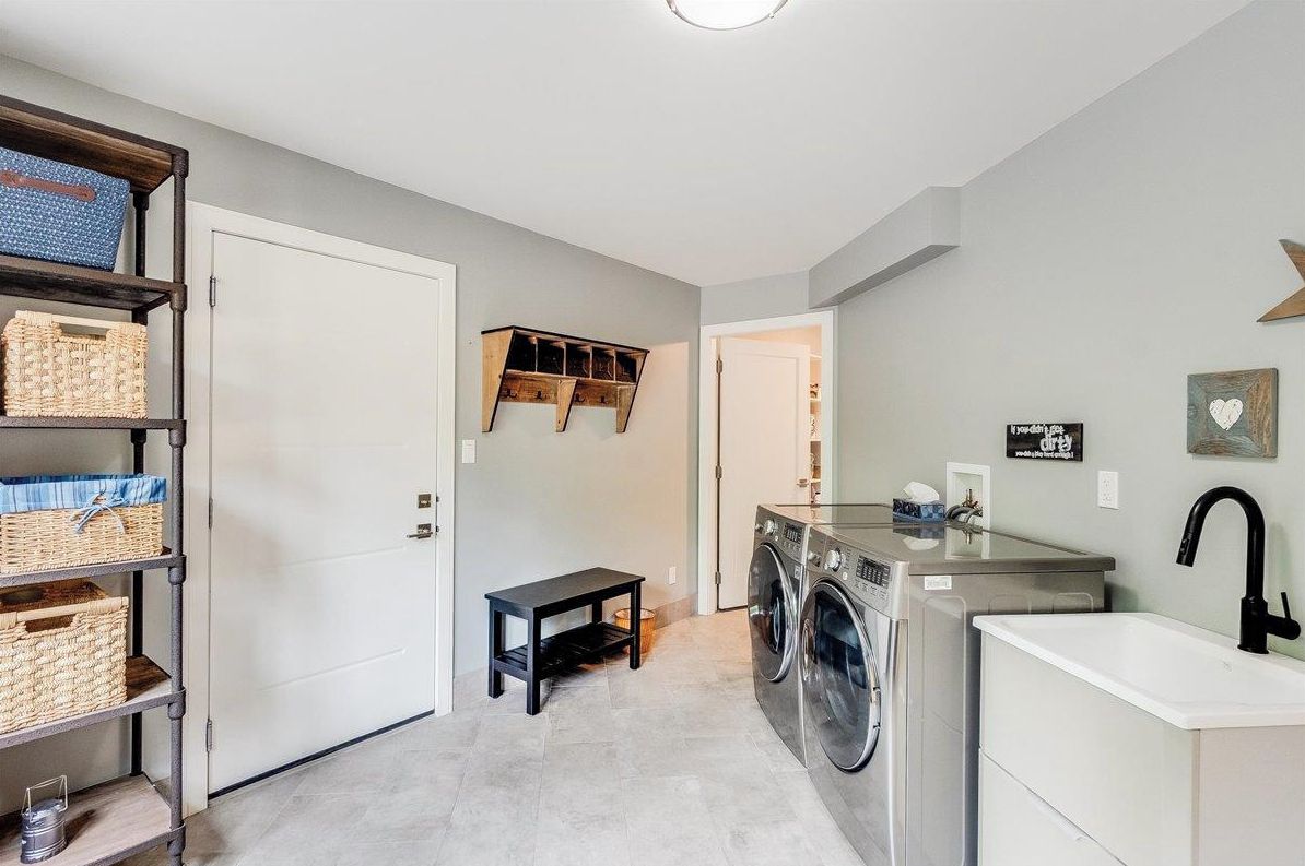 A laundry room with a washing machine, a sink, and a bench.