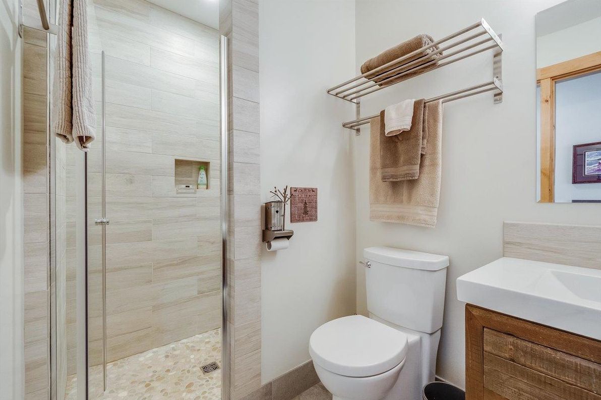 Une salle de bain avec une douche à parois de verre, des toilettes, un porte-serviettes et un lavabo avec un meuble en bois.