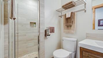 Une salle de bain avec une douche à parois de verre, des toilettes, un porte-serviettes et un lavabo avec un meuble en bois.