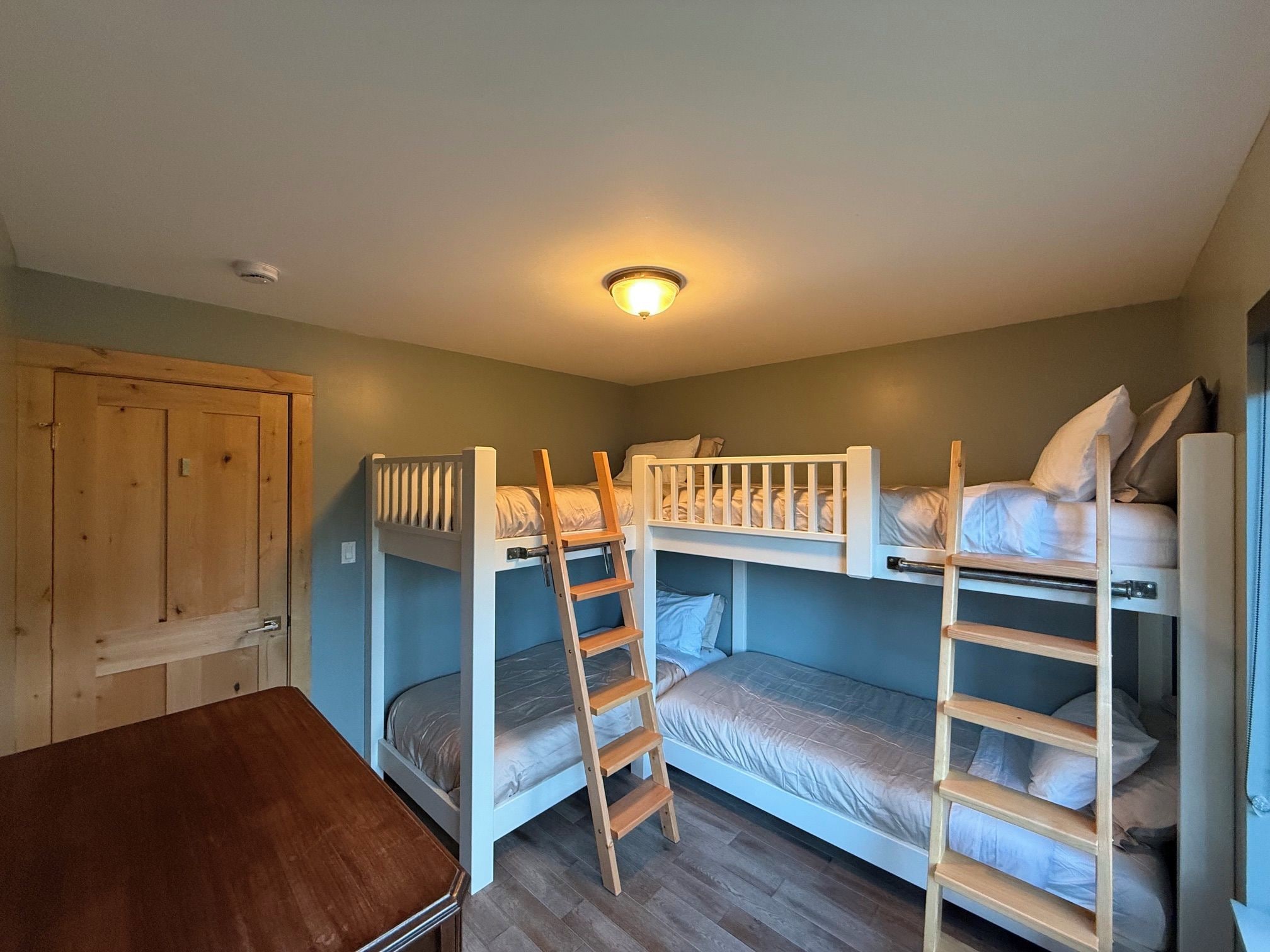 A room with bunk beds, a wooden desk, and a door.