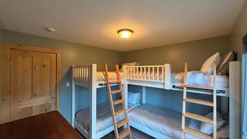 A room with bunk beds, a wooden desk, and a door.