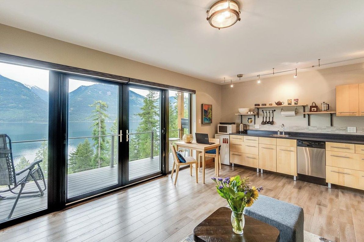 A modern kitchen with a view of mountains and a balcony with a chair.