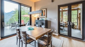 A dining area with a wooden table and chairs, a large window, and a view of the outdoors.