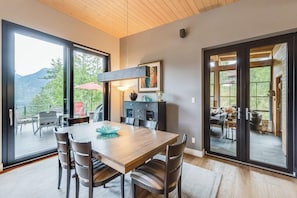 Uma sala de jantar com mesa e cadeiras de madeira, uma janela grande e vista para o exterior.
