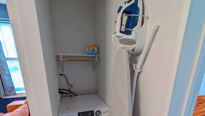 A compact laundry area with a washing machine and a drying rack. - 1 Bdrm Gem: Walkable, Downtown, Queen Bed (Detroit)