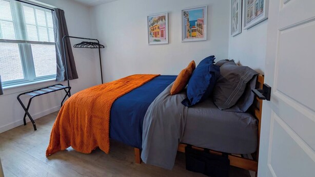 A bedroom with a bed, a window, a radiator, and wall art. - 1 Bdrm Gem: Walkable, Downtown, Queen Bed (Detroit)