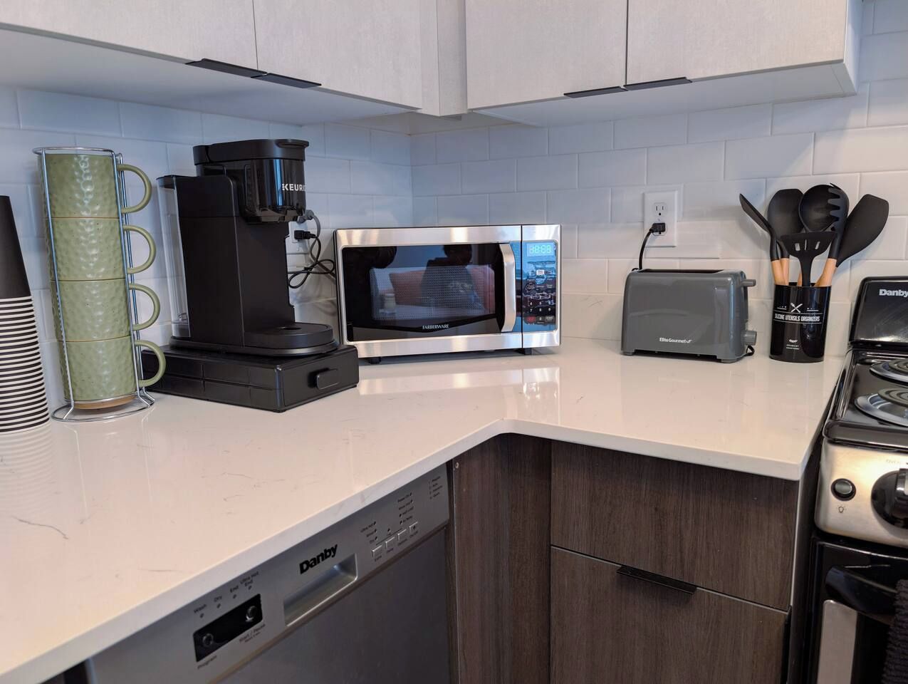 A modern kitchen with a built-in dishwasher, a coffee maker, a microwave, a toaster, and a stove.