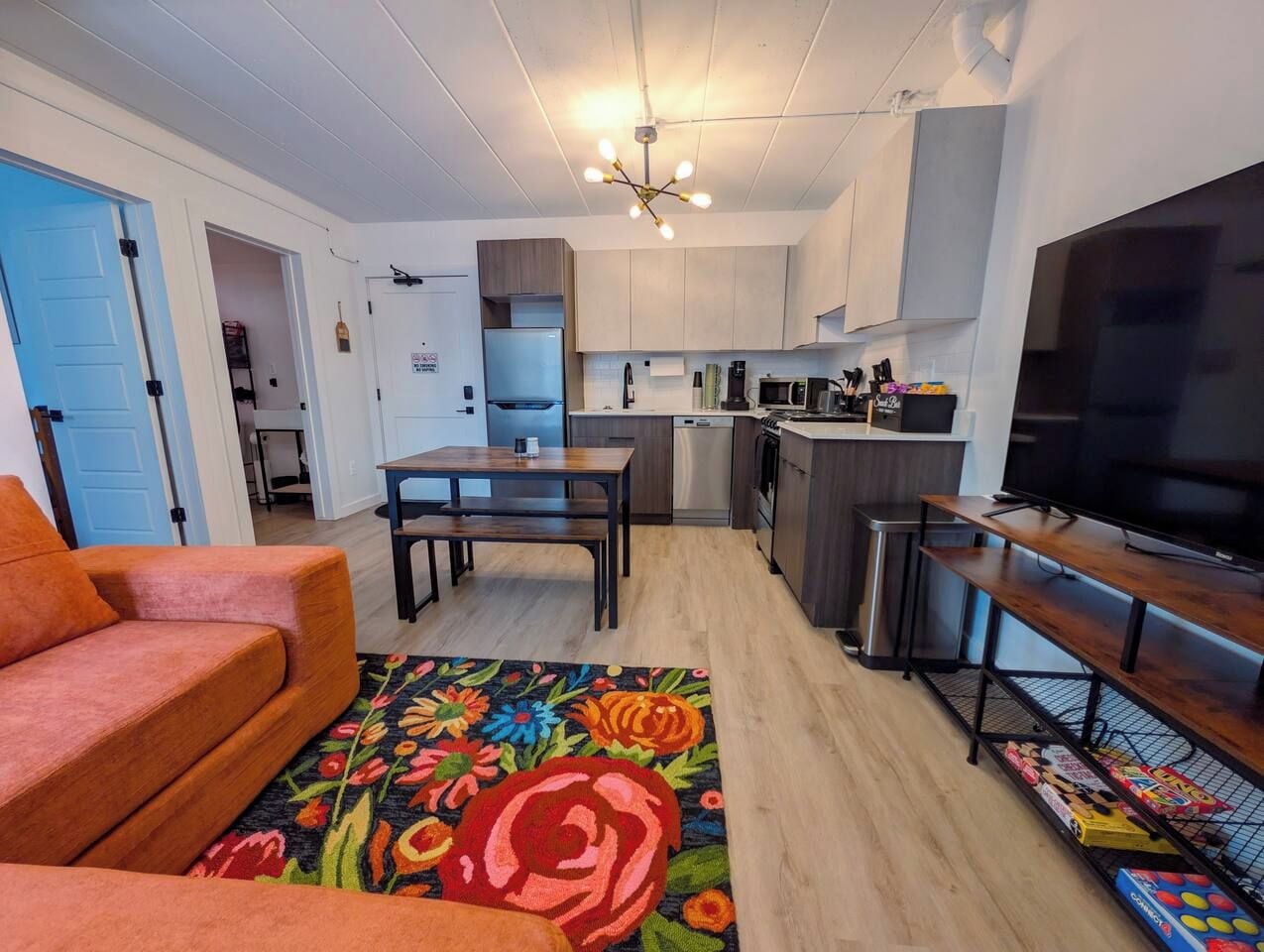 A compact living space with a kitchenette, a dining area, and a seating area with a sofa and a TV stand.