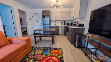 A compact living space with a kitchenette, a dining area, and a seating area with a sofa and a TV stand.