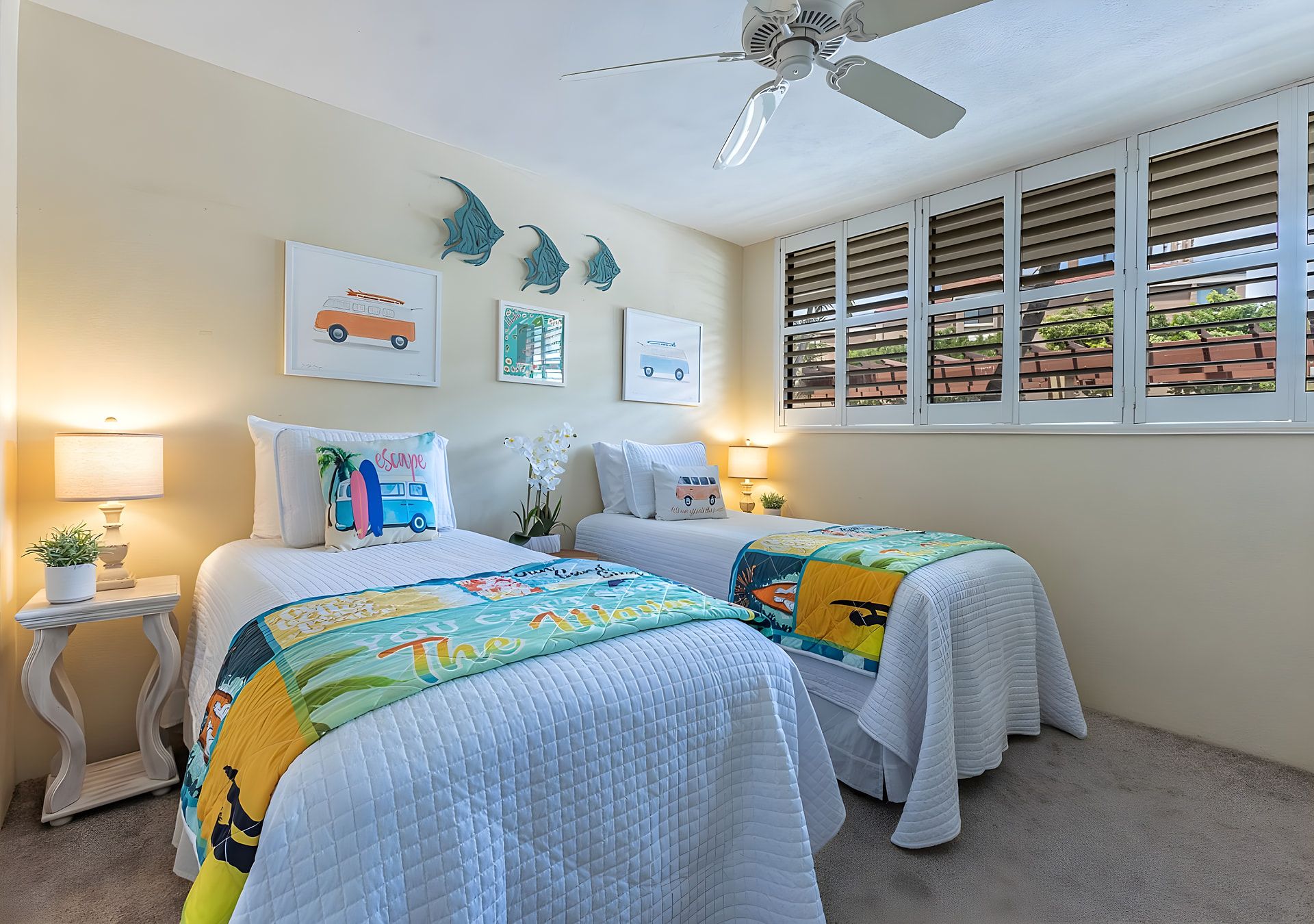 A bedroom with two beds, a ceiling fan, and artwork on the walls.