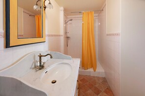 Ein Badezimmer mit einem weißen Waschbecken, einem Spiegel und einer Dusche mit gelben Vorhängen.