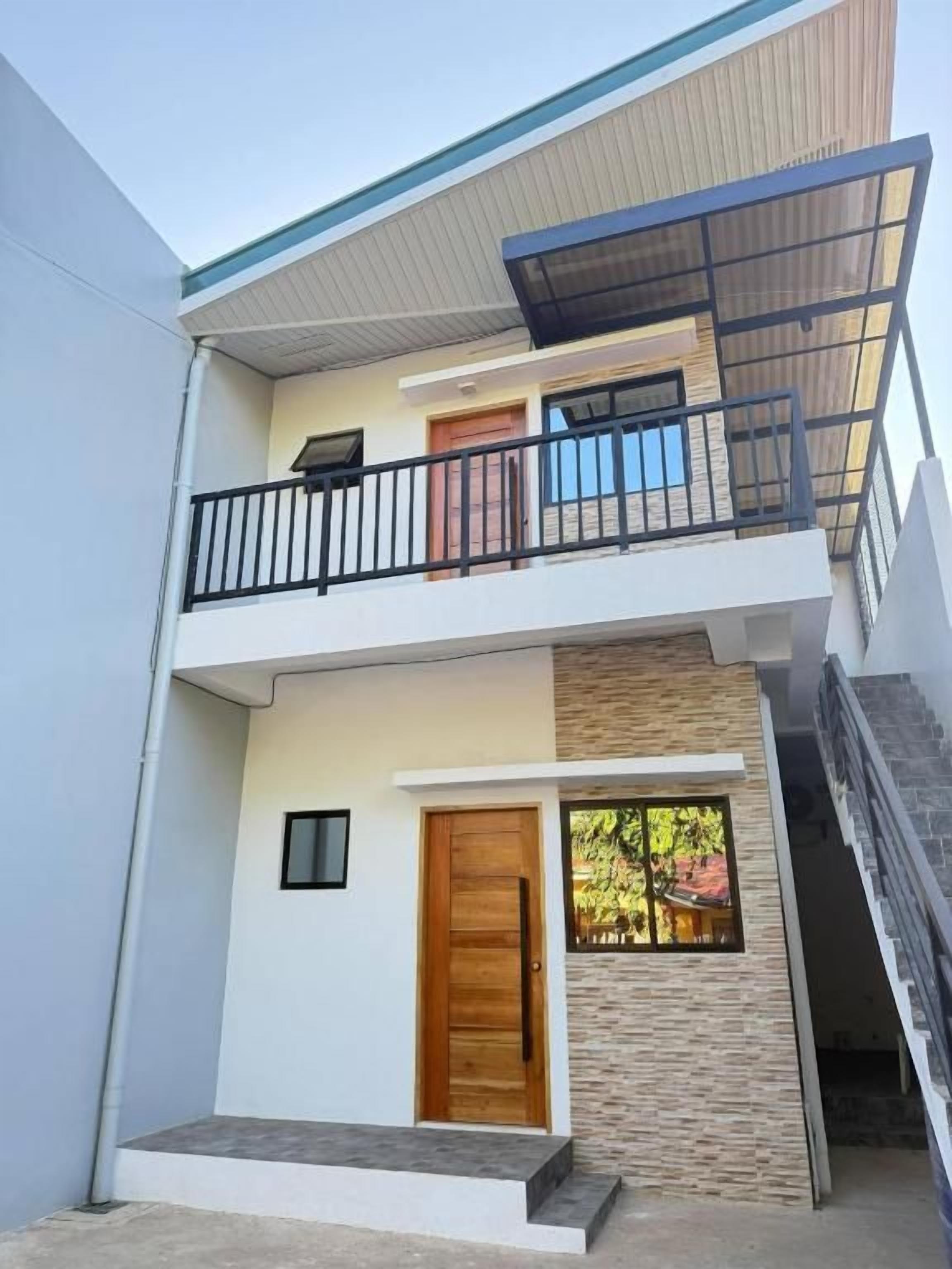 Ein zweistöckiges Gebäude mit einem Balkon, einer Holztür und einer Treppe, die zum oberen Stock führt.