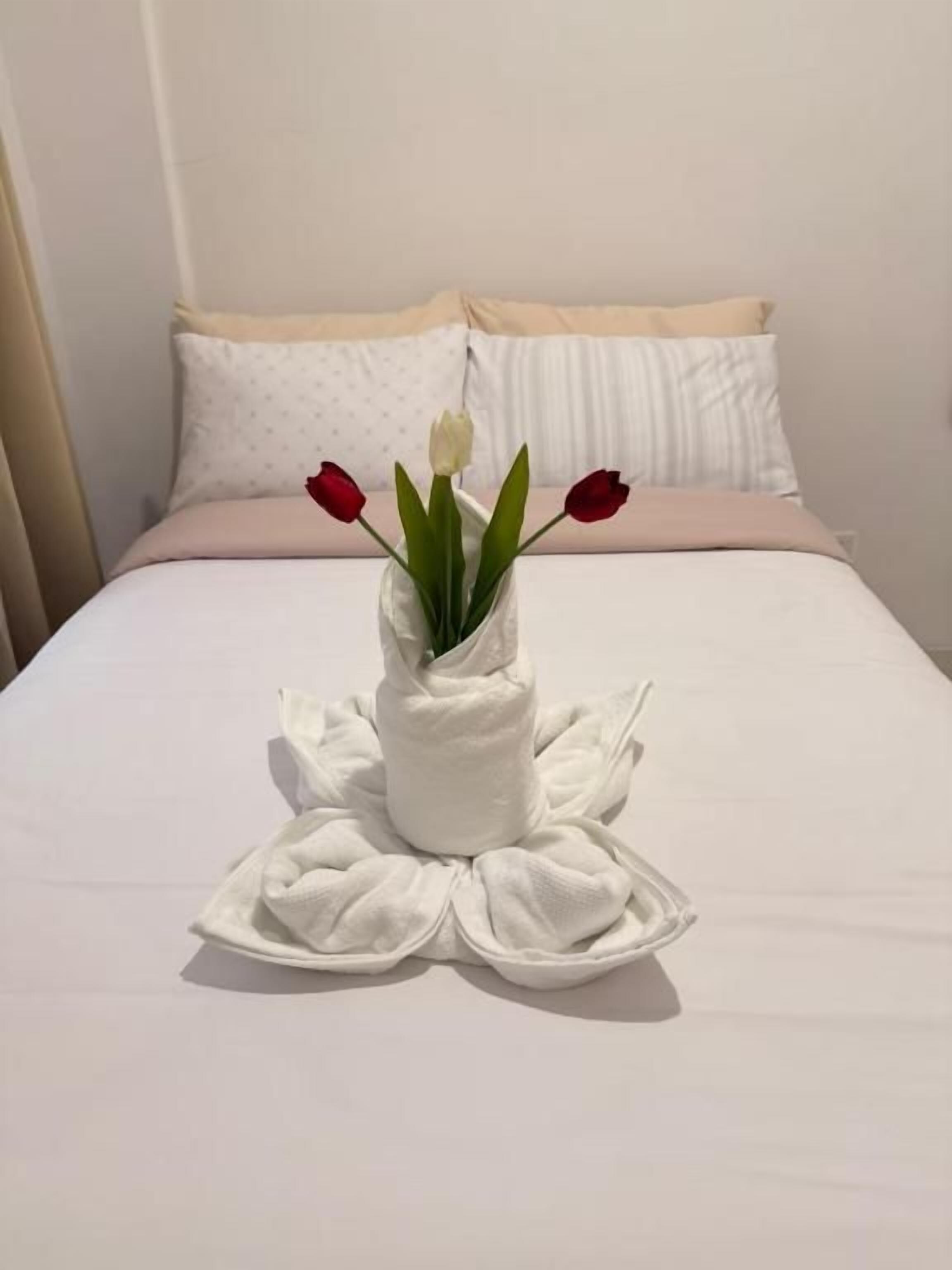 A bed with a white bedspread and a towel arrangement in the center.