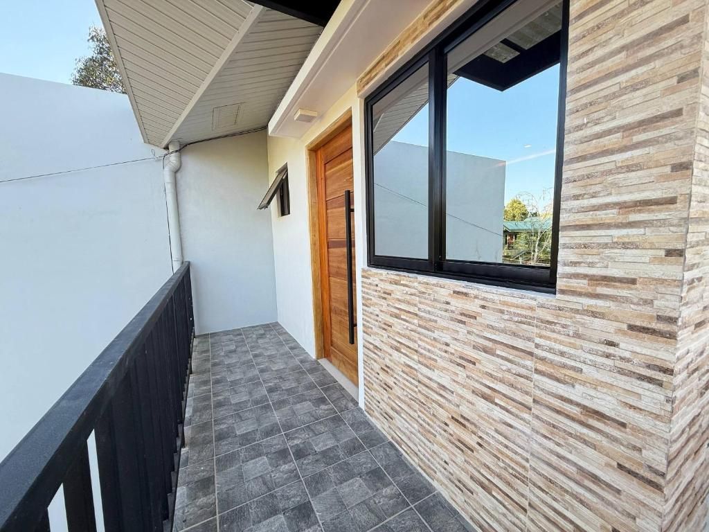 A modern exterior with a wooden door, a window, and a tiled floor.