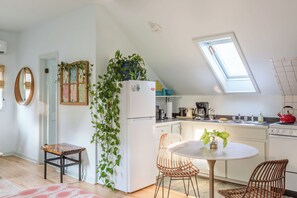 A modern kitchen with a skylight, white cabinetry, and a dining area with wicker chairs. - Sweet Sun-filled Studio in Algiers Point w Parking (New Orleans)