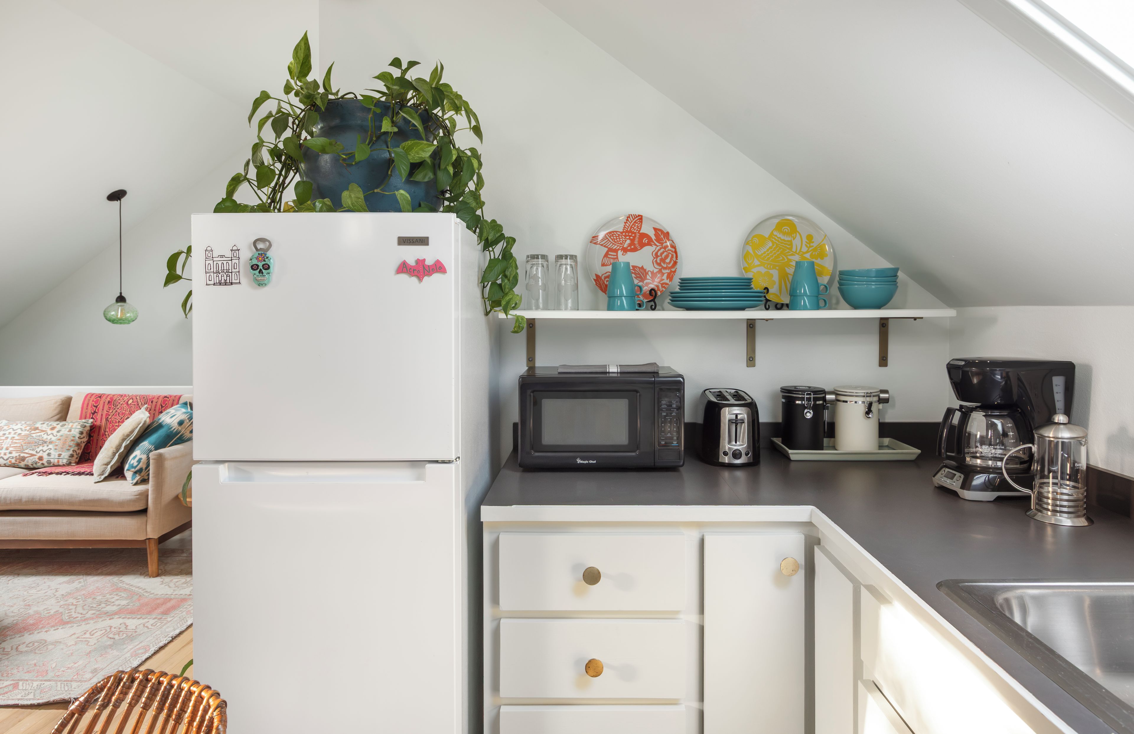 A kitchen with a white refrigerator, microwave, toaster, and coffee maker on the counter.