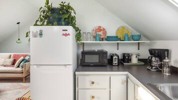 A kitchen with a white refrigerator, microwave, toaster, and coffee maker on the counter.