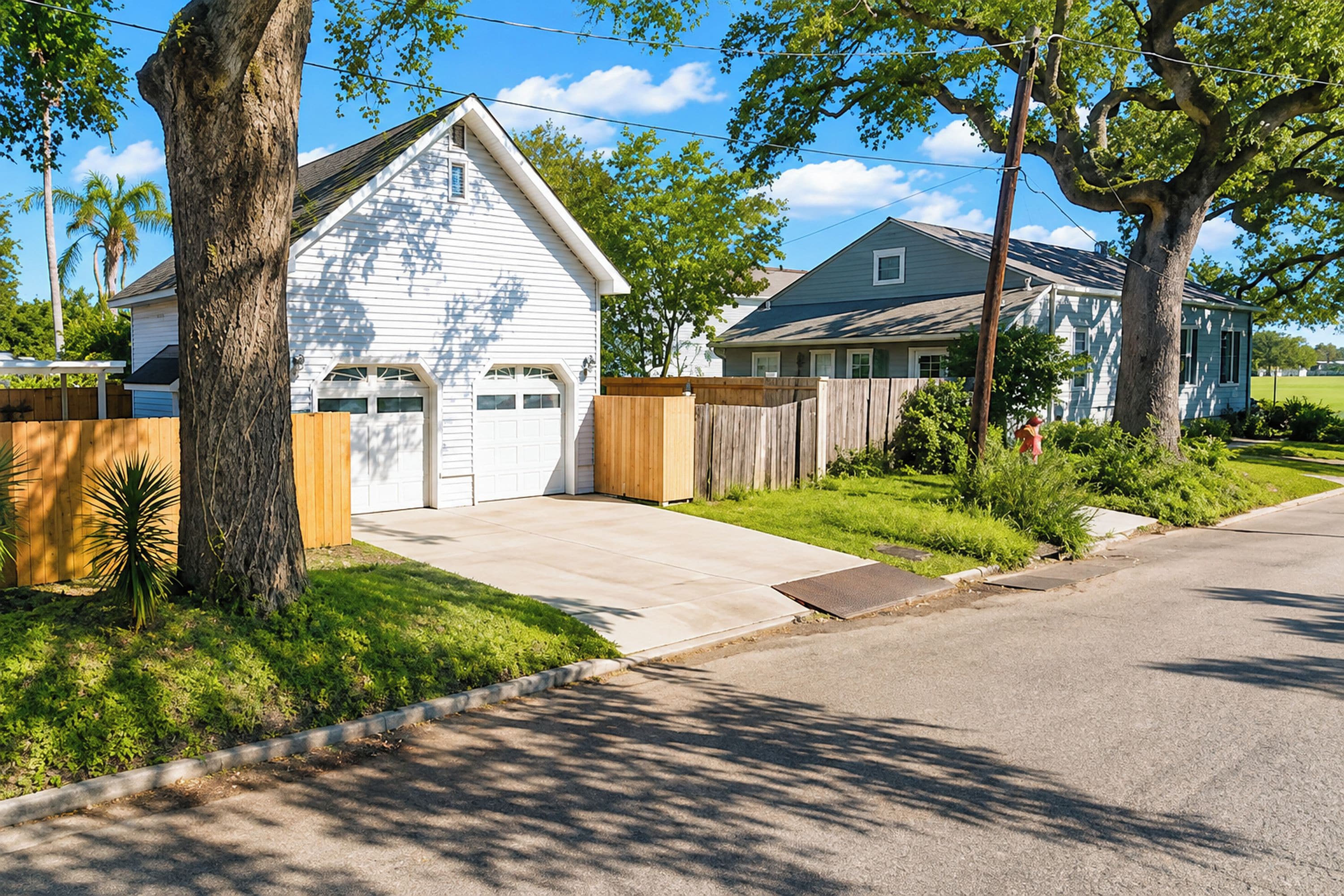 A residential street with houses, a driveway, and a sidewalk.