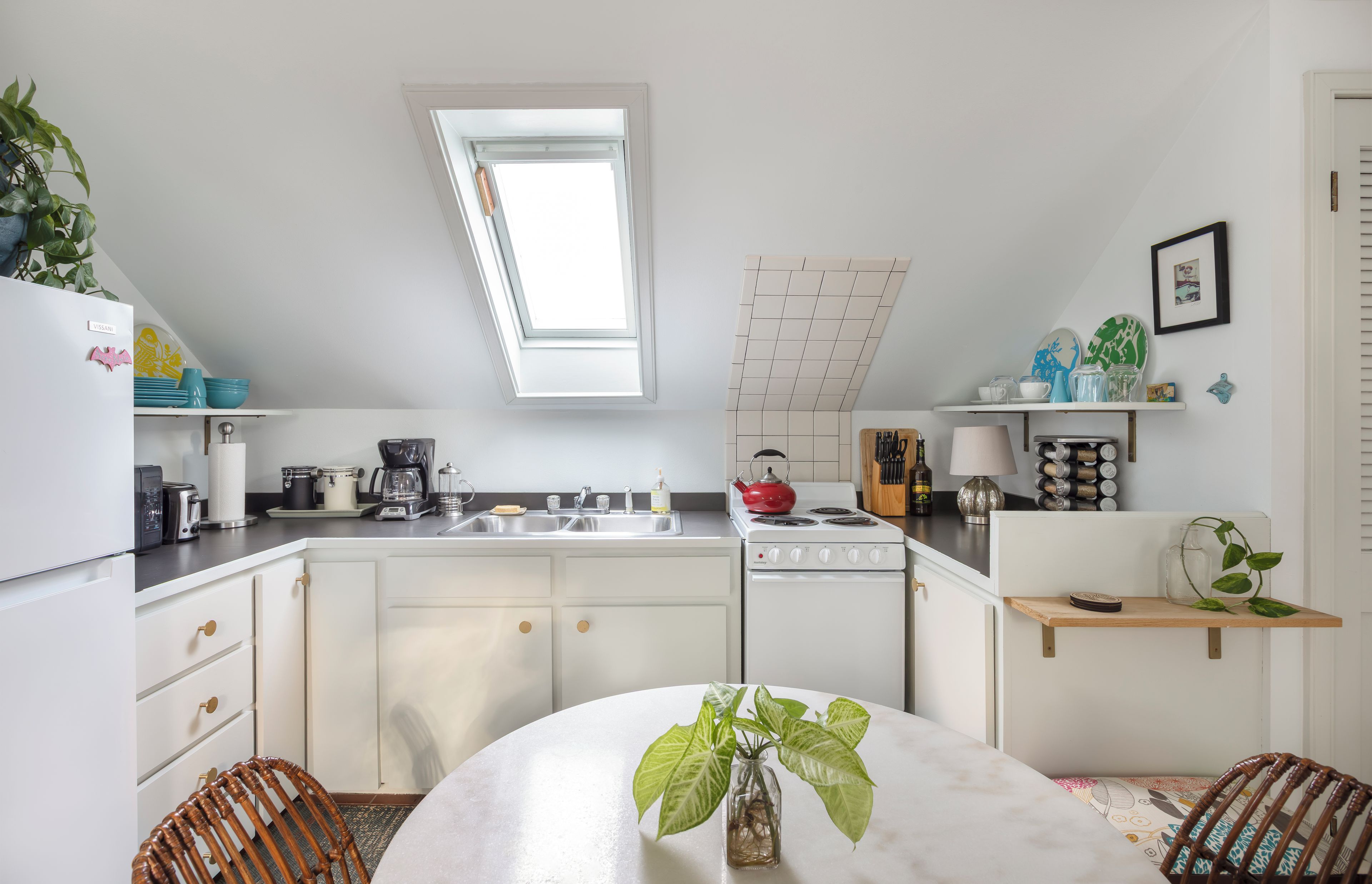 A modern kitchen with white cabinetry, a skylight, and a dining area with a round table.