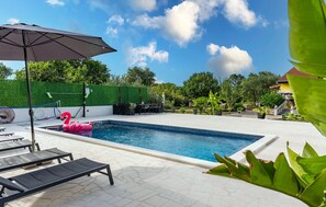 Une piscine avec des chaises longues et un flotteur en forme de flamant rose.