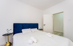 A hotel room with a large bed, a blue headboard, white bedding, and a small bedside table with a lamp. - Gorgeous home in Pridraga with private swimming pool, can be inside or outside (Pridraga)