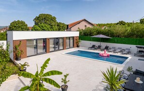A modern outdoor pool area with a contemporary building, lounge chairs, and potted plants. - Gorgeous home in Pridraga with private swimming pool, can be inside or outside (Pridraga)