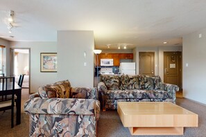 Ein Wohnzimmer mit zwei gemusterten Sofas, einem Holztisch und einem Essbereich mit Tisch und Stühlen.
