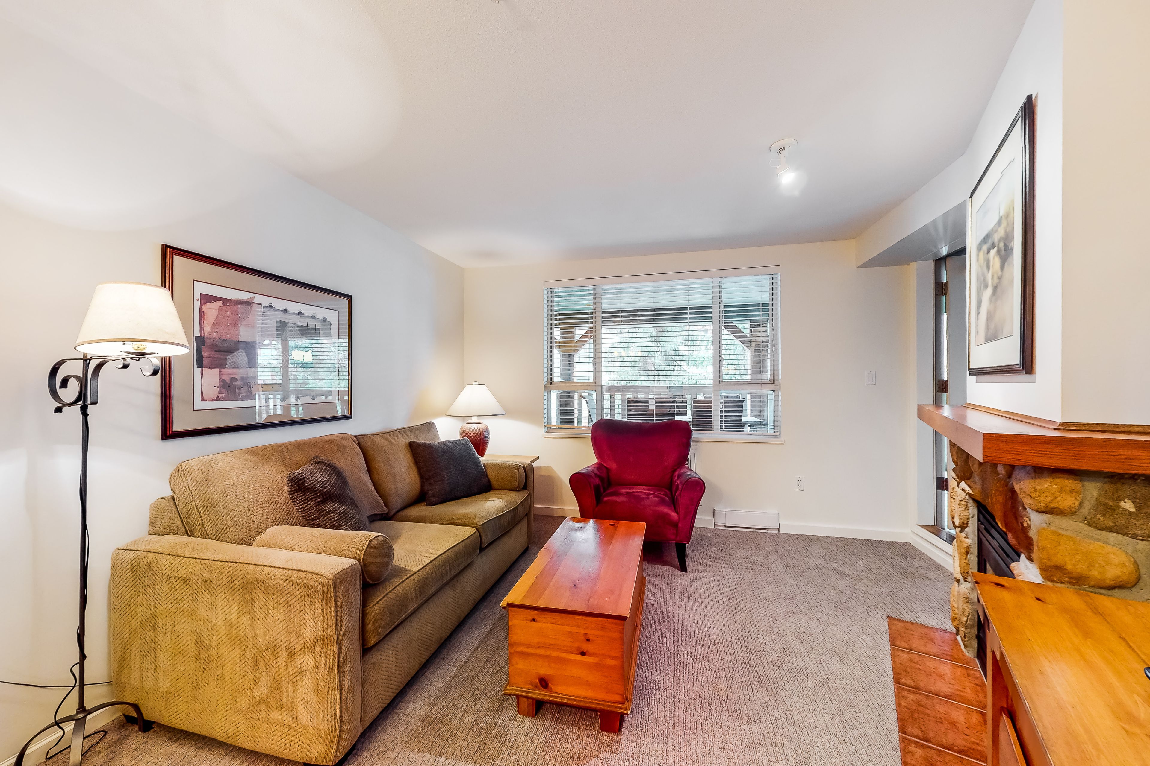 A living room with a sofa, armchair, coffee table, and fireplace.