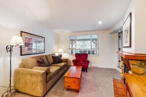 A living room with a sofa, armchair, coffee table, and fireplace.