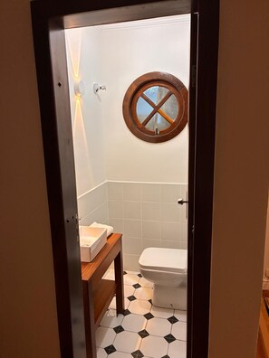 Une salle de bain avec des toilettes, un lavabo et une fenêtre avec un cadre en bois.