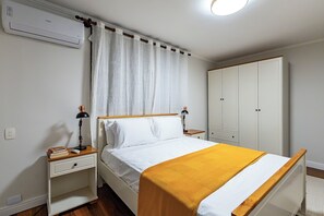 Une chambre à coucher avec un lit, des tables de chevet, une armoire et une fenêtre avec des rideaux.