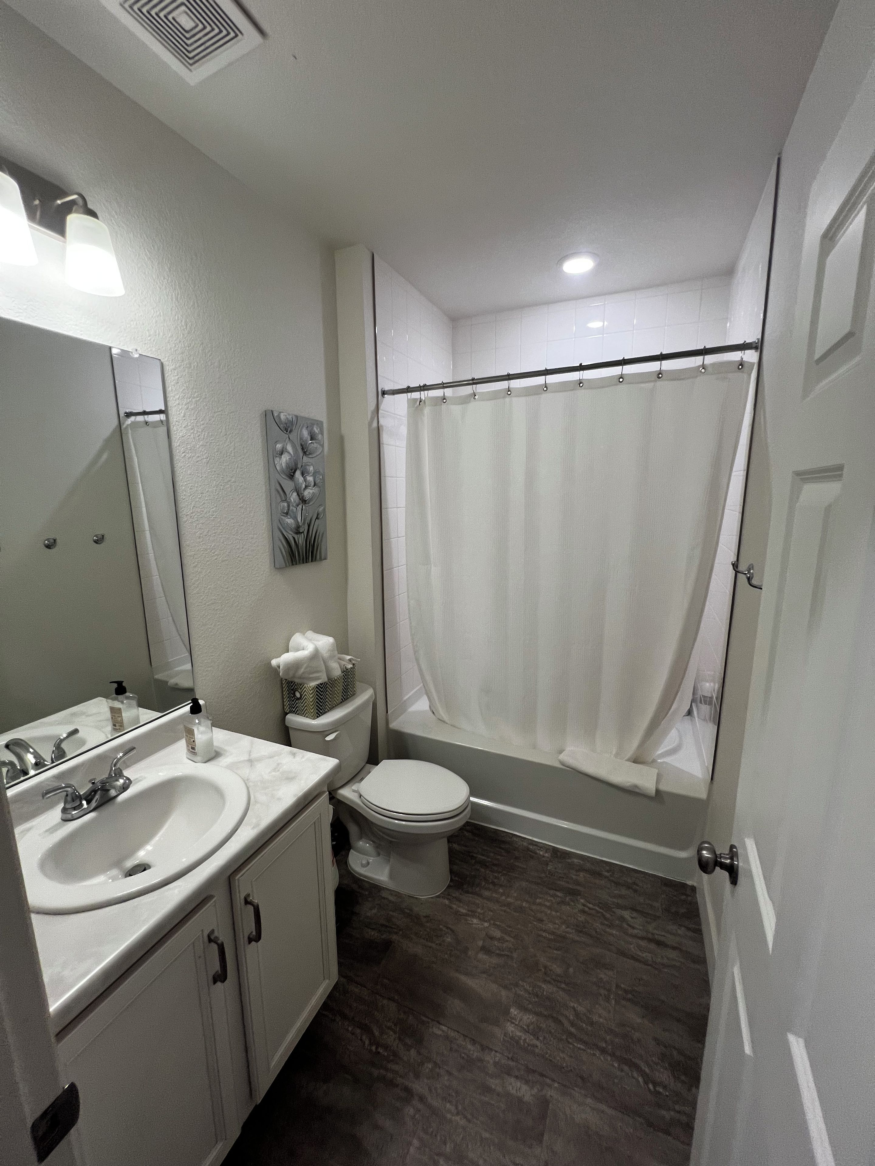 A bathroom with a sink, toilet, and shower curtain.