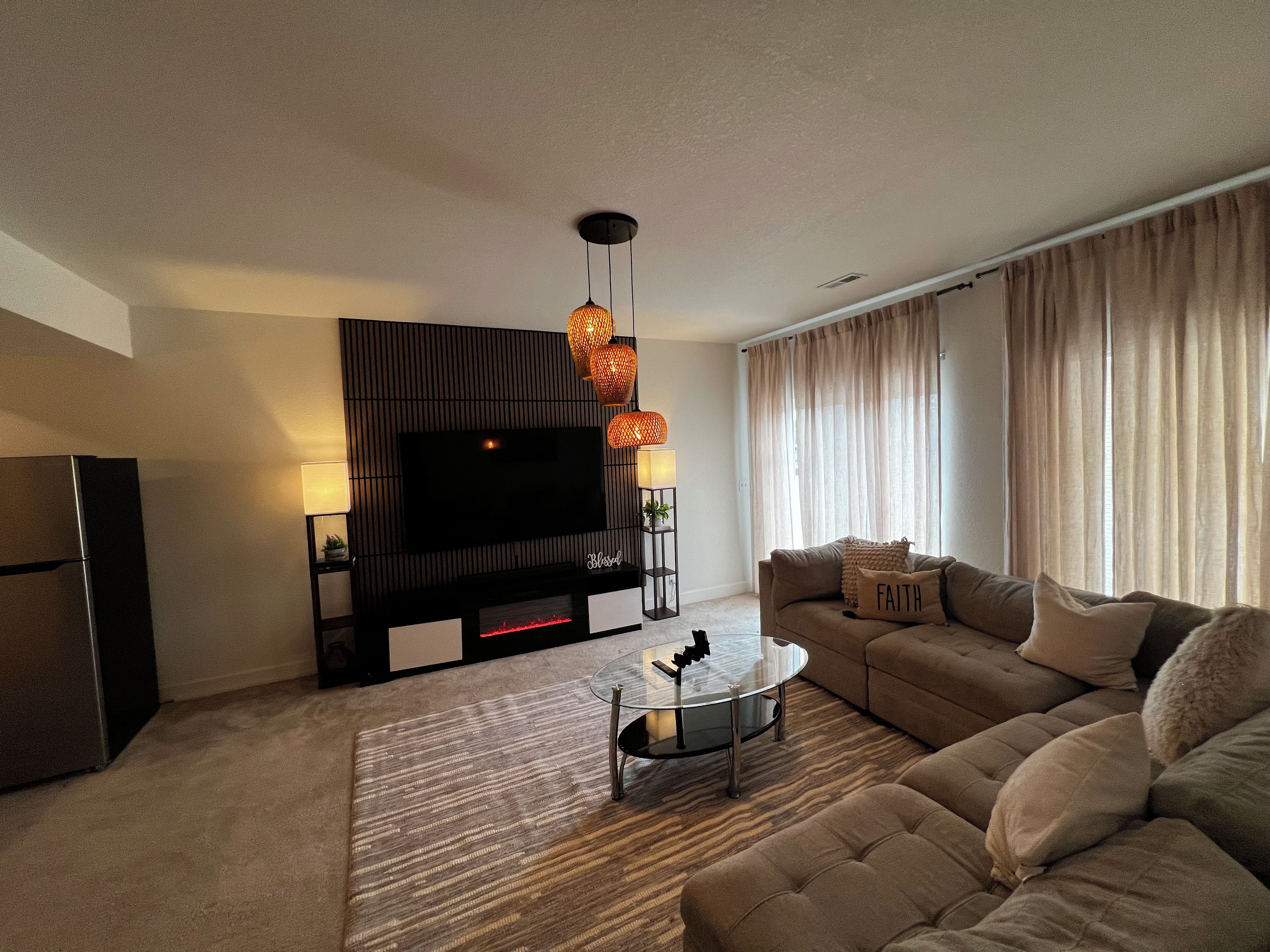 A modern living room with a flat-screen TV, a sofa, a coffee table, and a patterned carpet.