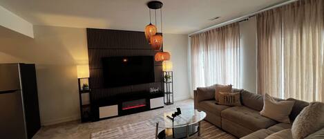 Una sala de estar moderna con un televisor de pantalla plana, un sofá, una mesa de centro y una alfombra estampada.