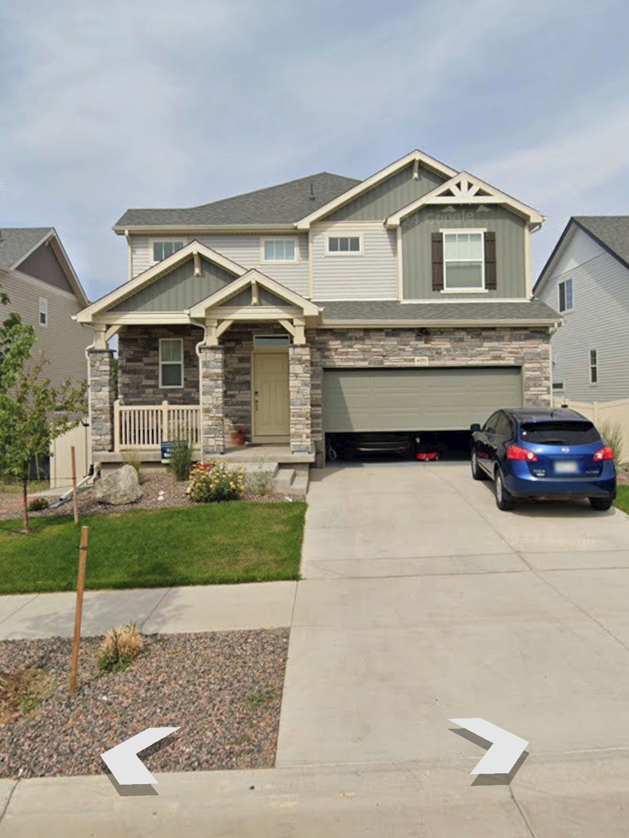 A two-story residential house with a stone facade, a garage, and a driveway.