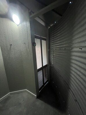 A narrow hallway with a door featuring a decorative glass panel and a vented window.