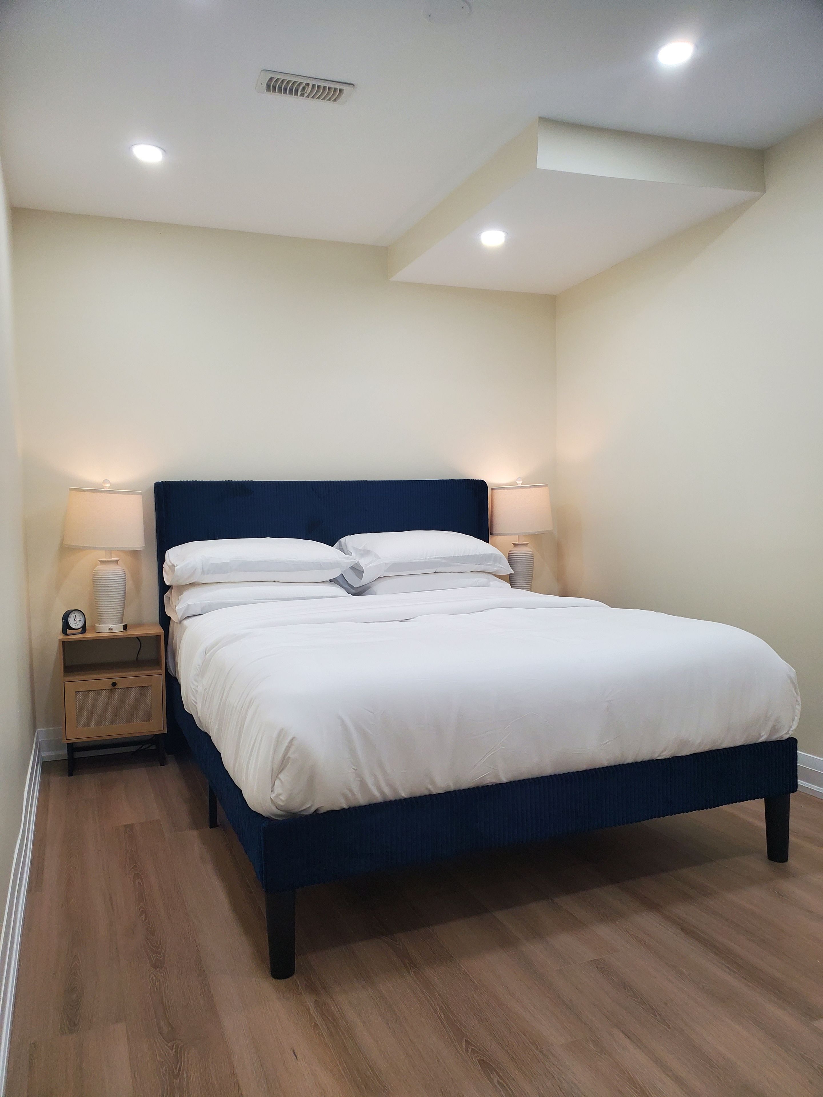 A bedroom with a bed, two bedside tables, and a ceiling light.