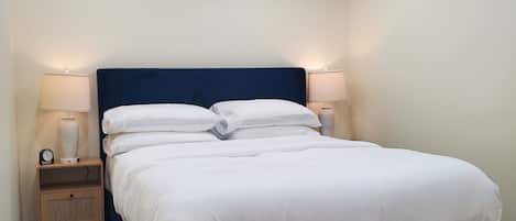 Une chambre à coucher avec un lit, deux tables de chevet et un luminaire fixé au mur.