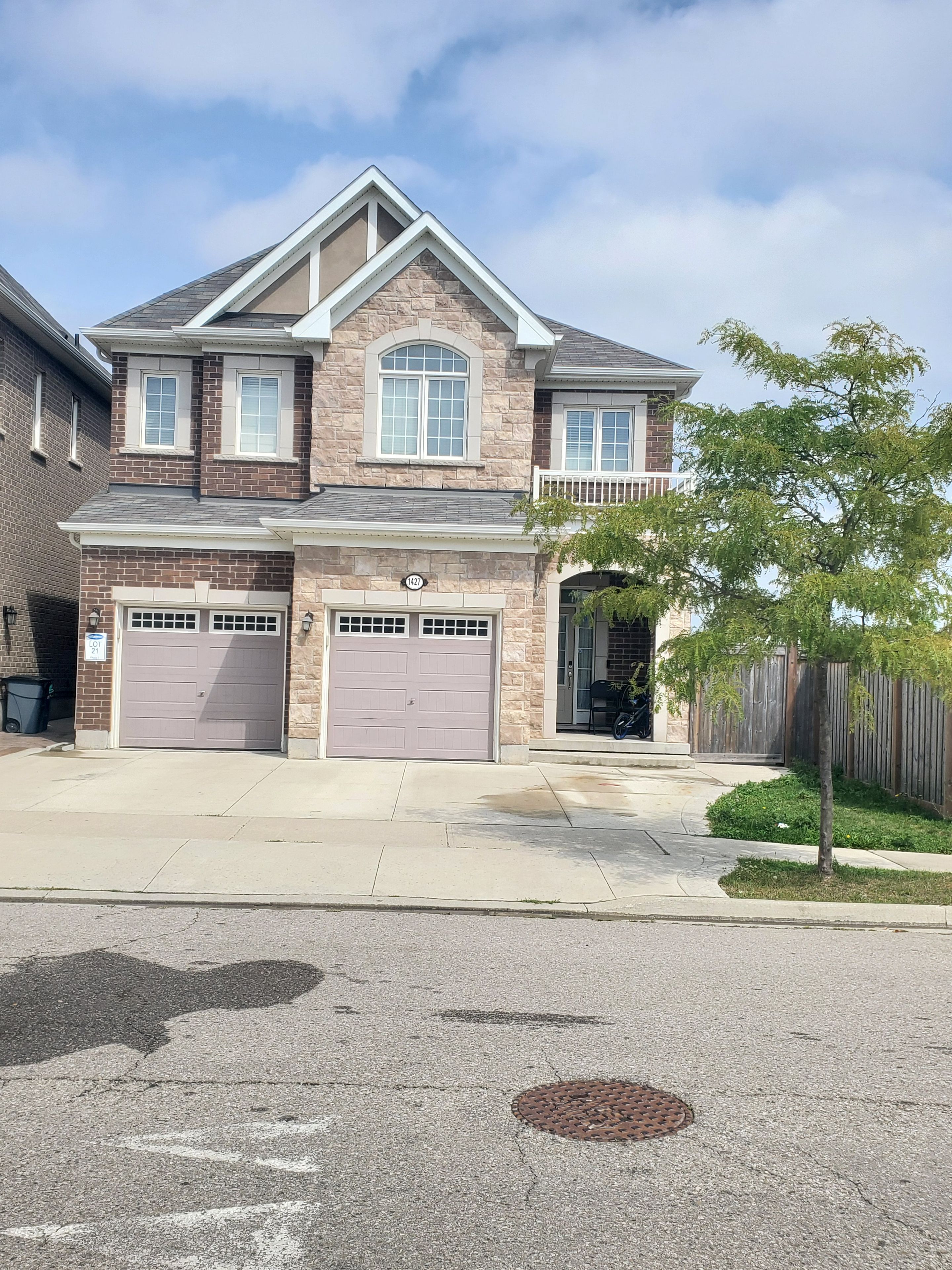 A two-story house with a garage, a stone facade, and a small front yard.