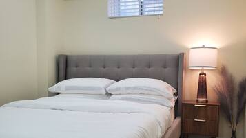 A bedroom with a bed, bedside table, lamp, and window.