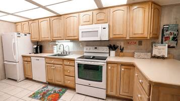 Une cuisine avec des meubles de rangement en bois, un four à micro-ondes, une cuisinière, un réfrigérateur et un évier.