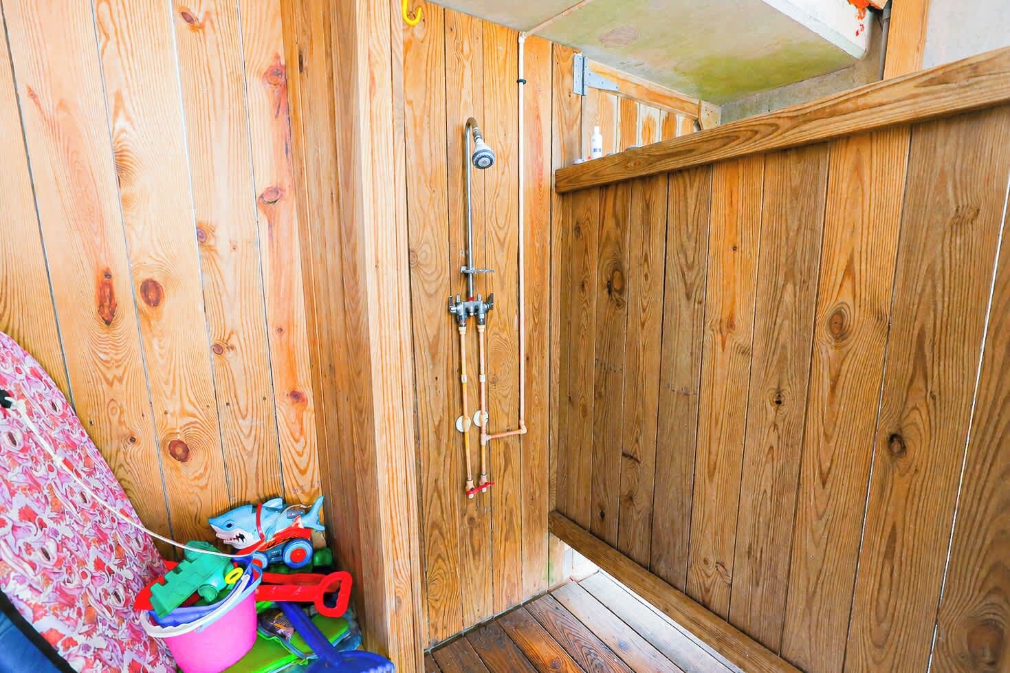 Een houten kamer met een douche, een houten deur en een klein raam.