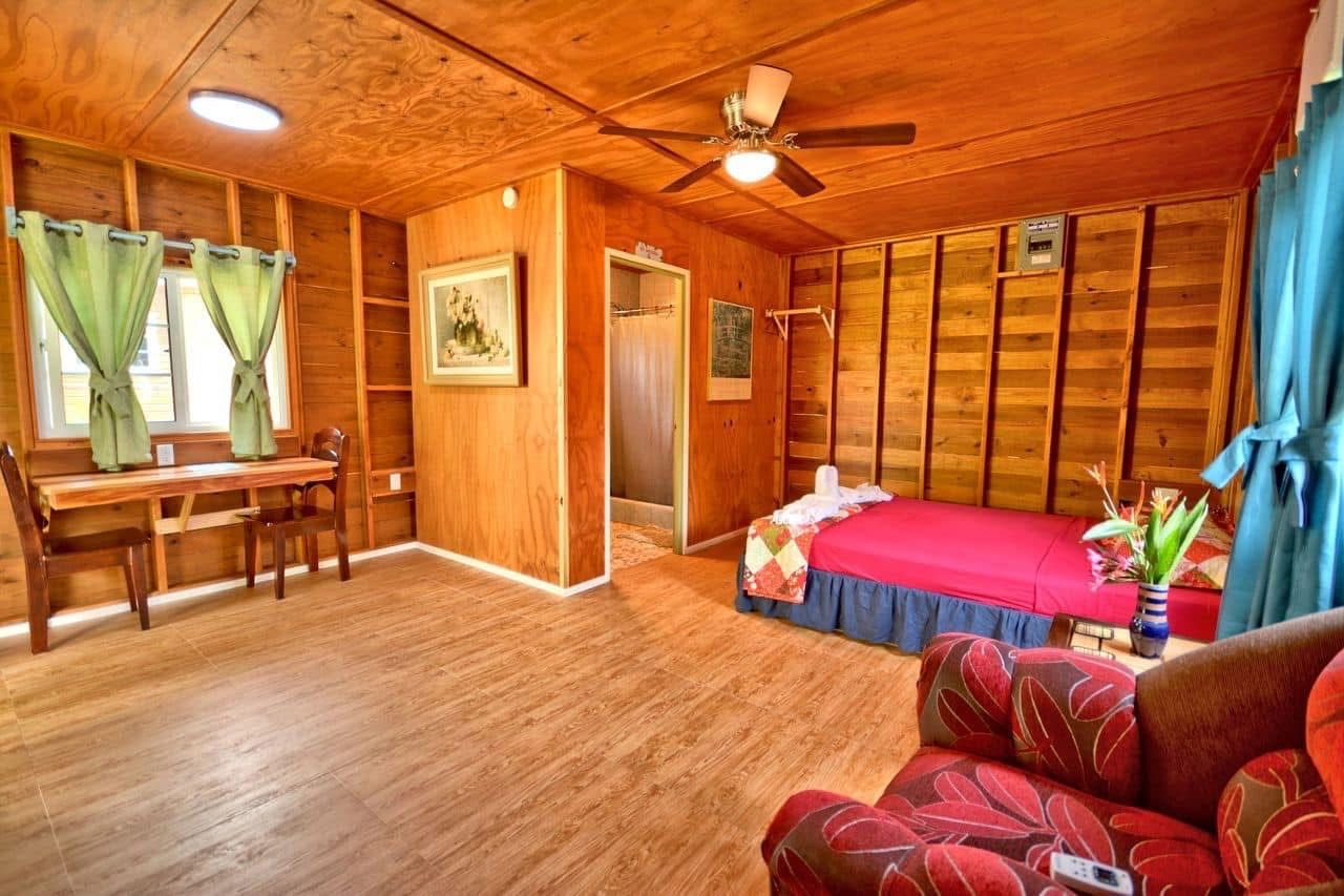 A wooden cabin interior with a bed, a desk, and a chair.