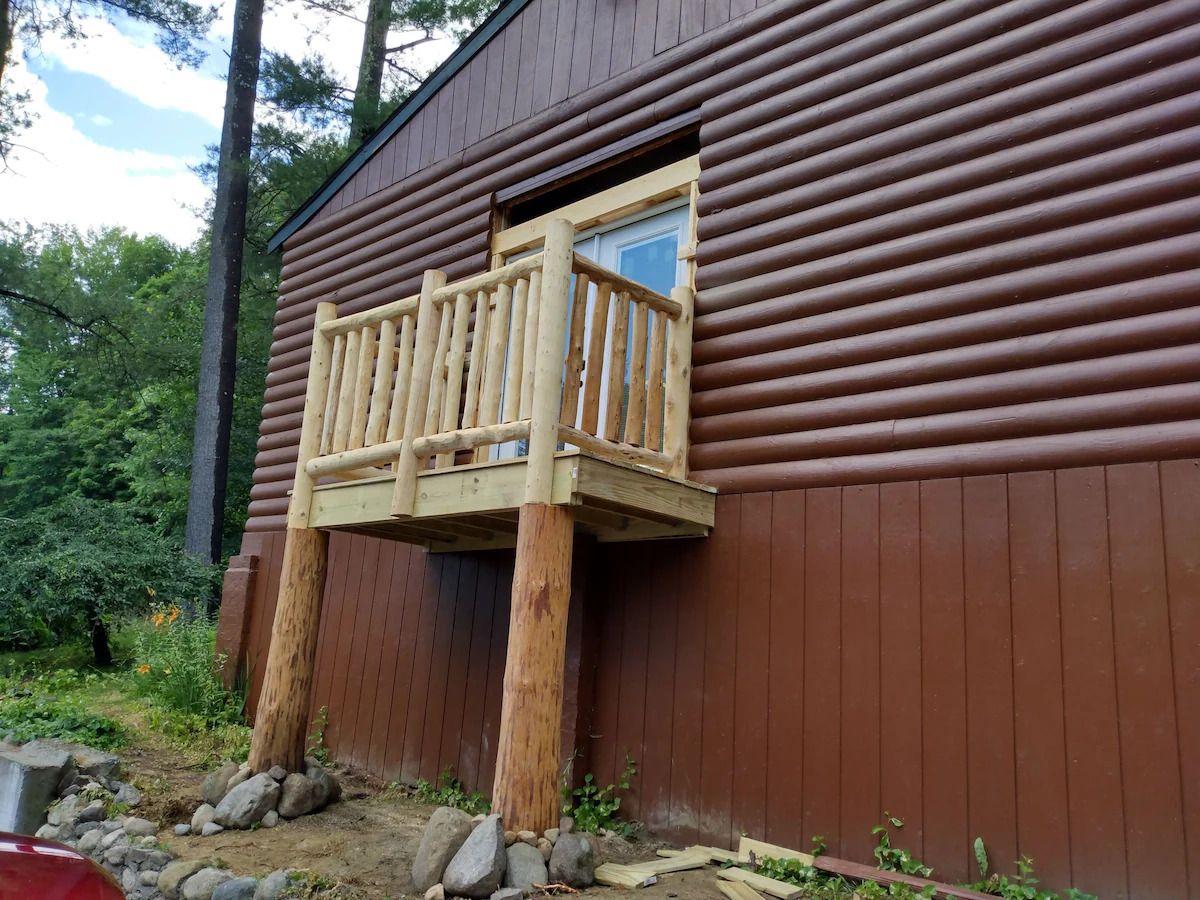A wooden cabin with a balcony attached to the side.